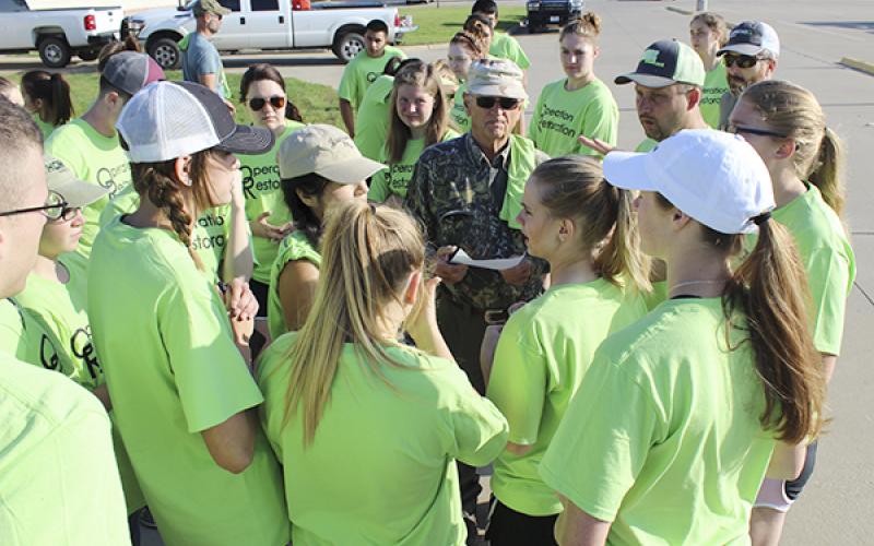 Volunteers gather at the Jacksboro High School ag building to split up in groups, gather tools and learn which locations they will be tackling.