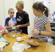 Jonathan Moser, center, measures ingrediants for sweet and salty cereal bars during the Jack County AgriLife Extension cooking camp Tuesday as Caiden Martin and Rebecca Bright look on.
