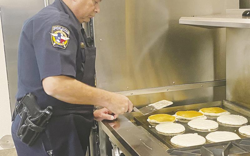 Jacksboro Police Department Lt. Brian Corb cooks up some pancakes during Breakfast with Santa at the parish Saturday, Dec. 10. Sausage, orange, juice, coffee and water were also on the menu. Photo/Brian Smith