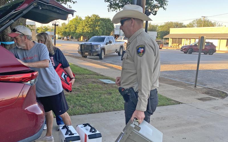 (Photo/Brian Smith) Patiently waiting is a part of any election. Here, election workers and a deputy work on loading a cart to bring into the courthouse.
