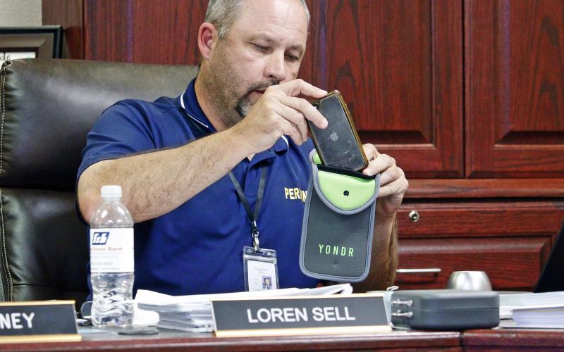 Perrin-Whitt CISD Superintendent Loren Sell demonstrates the Yondr pouch for school board members Tuesday, July 29. Students in seventh through 12th grade will be required to store their personal communication devices in the pouch during the school day. Photo/Ashley Anderson