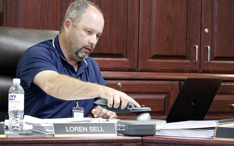 Perrin-Whitt CISD Superintendent Loren Sell shows the school board how to unlock the secured pouch that will store student personal communication devices during the school day this upcoming school year. Photo/Ashley Anderson