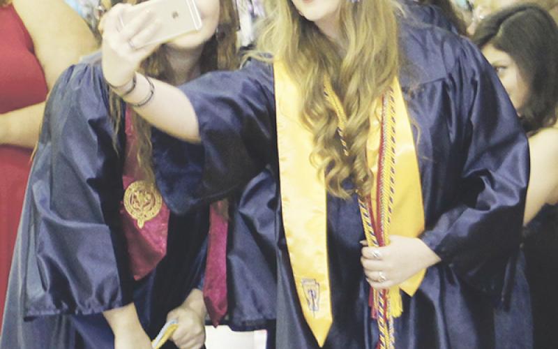 Two Perrin grads pause for a selfie during the recessional following the commencement ceremony Friday, May 27.