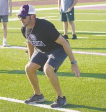 Assistant Coach John Bennett shows athletes taking part in strength and conditioning workouts proper positioning. Photo/Brian Smith