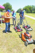 MPACT Ministries Director Mark McBride, left, checks out lawn mowers to teen workers Sunday as part of the week-long event. Around 270 volunteers and 90 adult leaders will be in town to do light construction work, mowing, weedeating around town for those who need it. Photo/Brian Smith