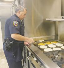 Jacksboro Police Department Lt. Brian Corb cooks up some pancakes during Breakfast with Santa at the parish Saturday, Dec. 10. Sausage, orange, juice, coffee and water were also on the menu. Photo/Brian Smith
