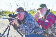 Jeff Rice (left) takes aim at a distant coyote that Larry Weishuhn is calling with his mouth predator call. Photo by Luke Clayton