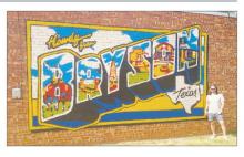 Graham artist Pecos McCool is shown by his recent mural in the city of Bryson on the south wall of City Hall on Depot Street. McCool said it’s his third mural and is similar to one he did in Graham last year.
