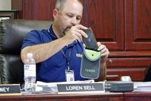 Perrin-Whitt CISD Superintendent Loren Sell demonstrates the Yondr pouch for school board members Tuesday, July 29. Students in seventh through 12th grade will be required to store their personal communication devices in the pouch during the school day. Photo/Ashley Anderson
