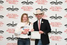 Elizabeth Hines, Jack County 4-H member, caught a calf during Fort Worth Stock Show and Rodeo's Calf Scramble, earning a $500 purchase certificate presented by Paxton Motheral, calf scramble committee member. 