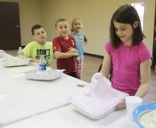 Douglas Brown, Caiden Martin and Jaci Robinson watch as Lainey Brown's elephant toothpaste grows.
